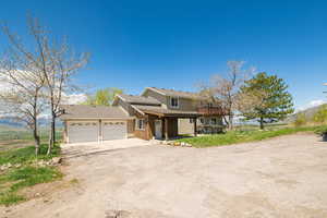 View of front of house with an attached garage, driveway, and a shingled roof