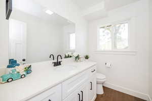 Bathroom with toilet, baseboards, vanity, and wood finished floors