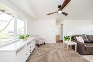 Living area featuring light carpet, a ceiling fan, and baseboards