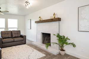 Carpeted living room with a ceiling fan and a tile fireplace