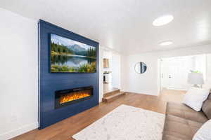 Living room with wood finished floors, a large fireplace, and a textured ceiling