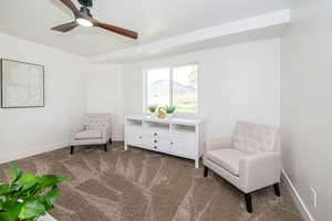 Living area featuring carpet flooring, ceiling fan, and baseboards