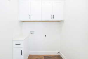 Washroom featuring hookup for an electric dryer, washer hookup, cabinet space, baseboards, and dark wood-type flooring