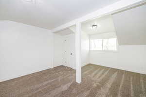Bonus room featuring lofted ceiling, carpet floors, and baseboards