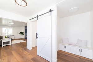 Mudroom with a barn door, wood finished floors, and baseboards