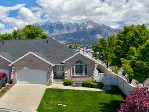 View of front facade with a garage, brick siding, driveway, a mountain view, and roof with shingles