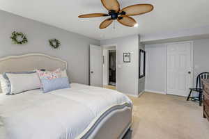Bedroom with light colored carpet, a ceiling fan, and baseboards