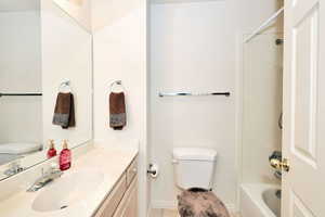 Bathroom featuring toilet, vanity, tile patterned flooring, shower / bath combination, and baseboards