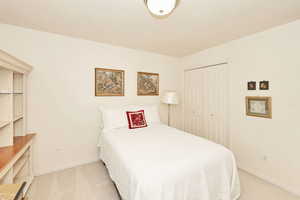 Bedroom featuring light carpet, baseboards, and a closet