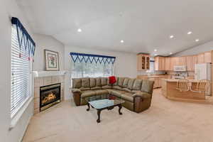 Living room with lofted ceiling, light carpet, a tile fireplace, recessed lighting, and baseboards