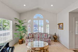 Sitting room featuring light carpet, plenty of natural light, vaulted ceiling, baseboards, and recessed lighting