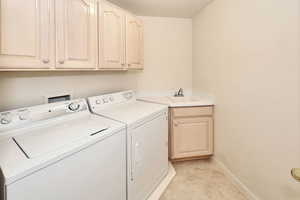 Laundry area with washer and dryer, cabinet space, baseboards, and light tile patterned flooring