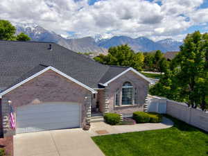 View of front of home with brick siding, driveway, a garage, a mountain view, and a shingled roof