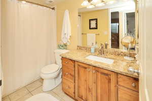 Full bath with tile patterned floors, toilet, vanity, and a shower with shower curtain