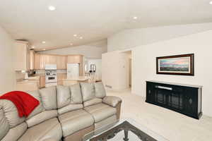 Living area with vaulted ceiling, recessed lighting, and light carpet