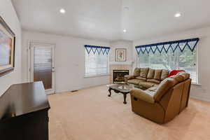 Living room featuring baseboards, a tile fireplace, recessed lighting, light colored carpet, and healthy amount of natural light