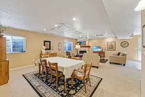 Dining room with light colored carpet, rail lighting, a fireplace, recessed lighting, and baseboards