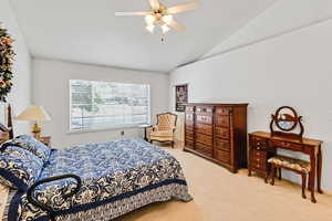 Bedroom with vaulted ceiling, light colored carpet, and ceiling fan