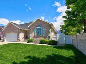 View of front facade with a gate, an attached garage, brick siding, and driveway