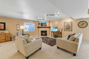 Living area with light carpet, a tile fireplace, track lighting, and baseboards