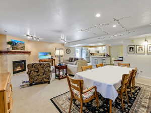 Dining room with light carpet, track lighting, a tiled fireplace, and baseboards