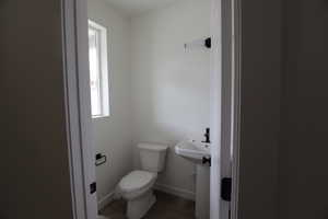 Bathroom with toilet, a sink, baseboards, and wood finished floors