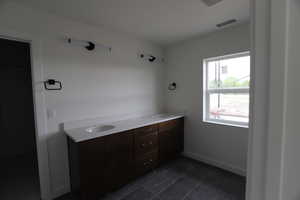 Bathroom with double vanity, baseboards, and tile patterned floors