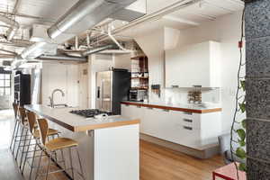 Kitchen with a sink, a breakfast bar area, white cabinetry, modern cabinets, and appliances with stainless steel finishes