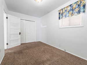 Unfurnished bedroom with carpet floors, a closet, and baseboards