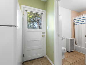 Entryway featuring light tile patterned floors, baseboards, and heating unit
