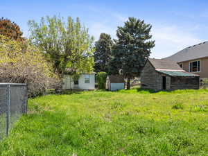 View of yard with a shed, fence, and an outbuilding