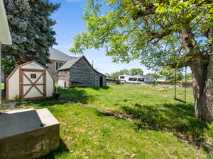 View of grassy yard featuring an outbuilding and a storage unit
