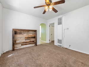 Unfurnished living room with a heating unit, arched walkways, carpet floors, ceiling fan, and baseboards
