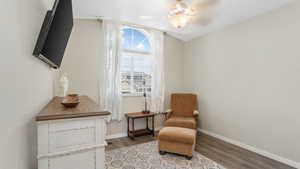 Living area featuring wood finished floors, baseboards, and ceiling fan