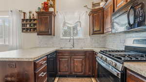 Kitchen with black appliances, a sink, light countertops, and decorative backsplash