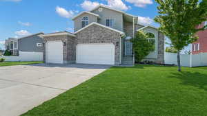 View of front of home with an attached garage, driveway, stone siding, and brick siding