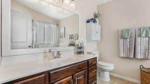 Bathroom with toilet, vanity, tile patterned floors, lofted ceiling, and baseboards