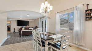 Dining area with arched walkways, tile patterned flooring, a chandelier, and baseboards