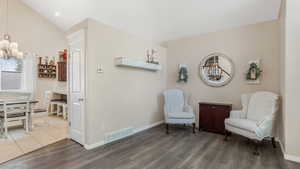 Living area with wood finished floors, baseboards, a chandelier, and high vaulted ceiling