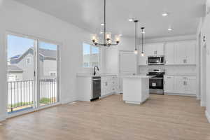 Kitchen featuring appliances with stainless steel finishes, a chandelier, light countertops, a center island, and light wood-style flooring