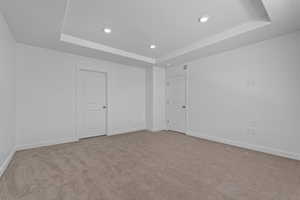 Unfurnished room featuring a tray ceiling, recessed lighting, light carpet, and baseboards