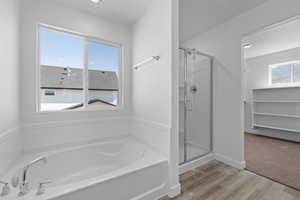 Full bathroom with a stall shower, a bath, wood finished floors, and recessed lighting