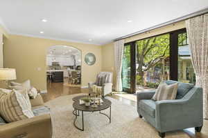Living area with arched walkways, recessed lighting, light wood-style flooring, ornamental molding, and baseboards