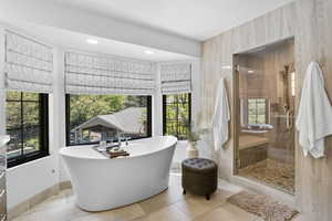 Full bathroom featuring tile patterned floors, a stall shower, a freestanding tub, and recessed lighting