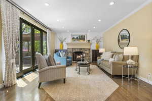 Living room featuring crown molding, baseboards, recessed lighting, a fireplace, and wood finished floors