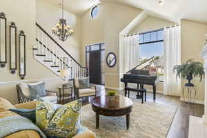 Sitting room featuring plenty of natural light, a chandelier, wood finished floors, stairs, and high vaulted ceiling