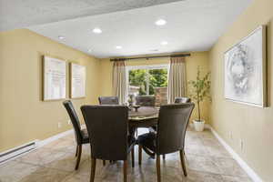 Dining space with a baseboard heating unit, a textured ceiling, recessed lighting, baseboards, and light tile patterned floors