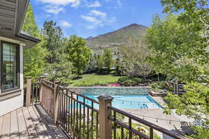 Outdoor pool featuring a deck with mountain view and a lawn