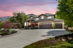 View of front of home with concrete driveway, an attached garage, a mountain view, and a shingled roof