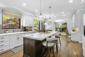 Kitchen featuring arched walkways, a center island, tasteful backsplash, white cabinetry, and recessed lighting